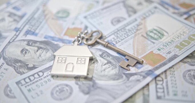 House key with home symbol on US dollar bills. Concept of property ownership, mortgage loan, housing market, investment, and financial success.