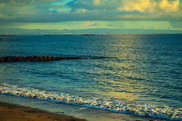 Ocean waves washing sandy beach with golden evening light