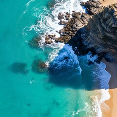 Aerial view of turquoise ocean waves crashing against rocky coastline and sandy beach