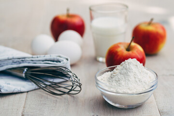 flour, apples and glass of milk on table