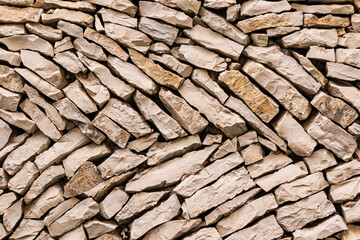 Abstract background of laying a wall made of small natural stones. stone texture. A sample of laying and building a wall made of natural material.