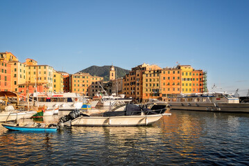 Scorcio del porto di Camogli con barche ormeggiate e luce dorata sul mare	
