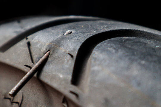 Close up A motorbike tubeless tire that is stuck in iron nails, this can cause a leak and must be repaired immediately. 