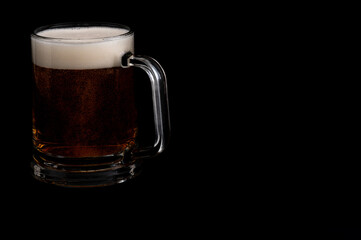 Dark beer in glass mug on black background – studio glassware