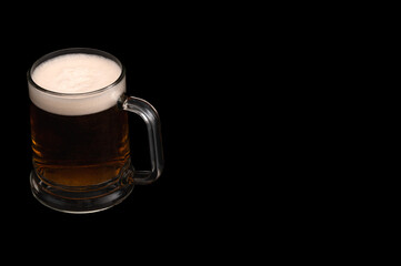 Dark beer in glass mug on black background – studio glassware
