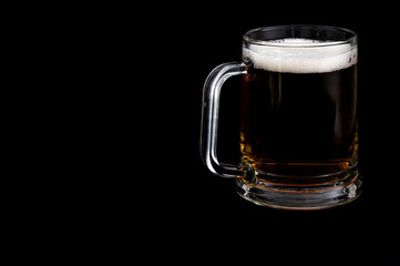Dark beer in glass mug on black background – studio glassware