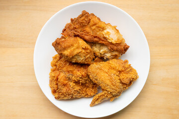 Crispy fried chicken in white plate on wood table