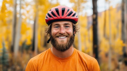 A man with a beard and a red helmet is smiling. He is wearing an orange shirt. Concept of happiness and adventure