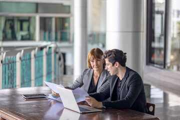 Conversation or group discussion among business team members from different generations, cultures, and diverse ethnicities outside of the main office. Group of people use computer to get information