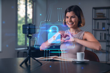 Smiling woman making heart gesture in front of camera with cybersecurity padlock concept overlay in modern home office background setting.