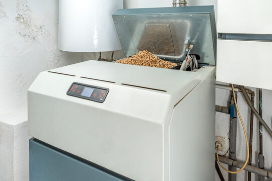 Close-up of biomass boiler with wood pellets for sustainable home heating.