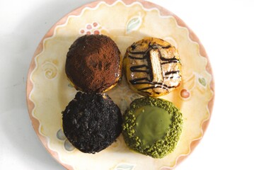 Top view of assorted sweet donuts with colorful toppings on a decorative ceramic plate