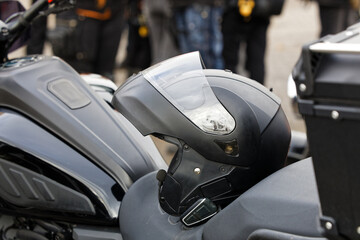 Closeup black moto helmet on motorcycle handlebars against blurred background. Shallow focus.