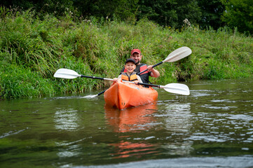 Father and son kayaking together on a scenic river on a sunny summer day enjoying outdoor adventure and family bonding