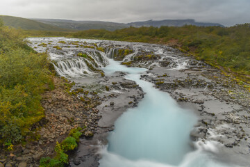 Blue waterfall on the river in cloudy weather