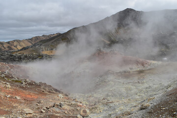 Smoke coming from a volcano, colorful mountains and rocks