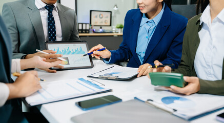 Business documents on office table with smart phone and calculator digital tablet and graph business with social network diagram and two colleagues discussing data working in the office
