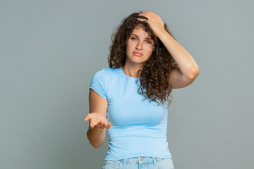 Young woman visibly disappointed upset after losing game or receiving bad news expressing sad negative emotions. Girl on gray background shows frustrated unhappy facial expression and discouraged mood
