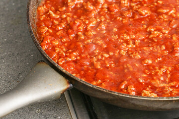 Spaghetti sauce with minced meat cooking in pan. Traditional tomato sauce bolognese. Homemade preparation of tasty pasta meal. Fresh red stew with pork meat. Rustic cuisine closeup cooking view.