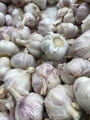 Fresh garlic bulbs piled together creating a textured background with purple streaks visible