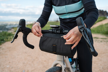 Cyclist adjusting handlebar bag on gravel bike during scenic ride