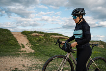 Young female cyclist pushing gravel bike on country road