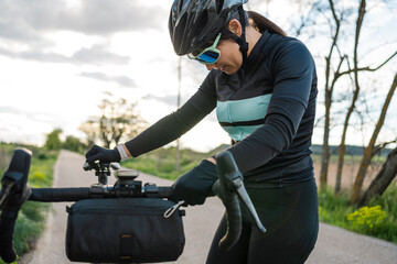Young woman cyclist adjusting her gravel bike on country road