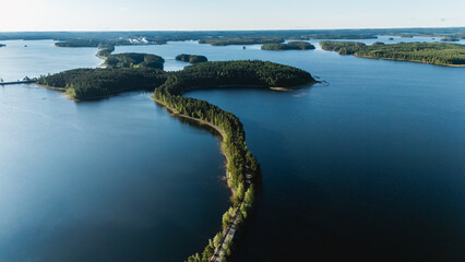 Majestic lakes and lush forests define the picturesque landscape of Punkaharju, Finland. The tranquil waters reflect the clear sky, inviting outdoor enthusiasts to explore this breathtaking area.