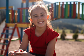 Smiling child girl playing on a colorful playground structure in a sunny park, enjoying a fun and active outdoor moment.