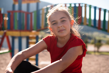 A happy child girl playing on a colorful playground structure in a sunny park, enjoying a fun and active outdoor moment.