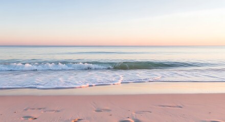 Gentle ocean waves wash ashore on a sandy beach at sunrise