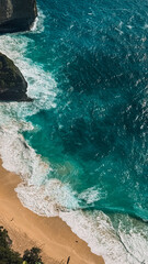 Aerial view of the turquoise ocean near Bali and Nusa Penida. Clear water, bright sunlight, and vibrant coastal tones showing the beauty of the tropical seascape from above.