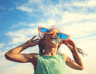Happy little girl in big sunglasses looking at the sun.