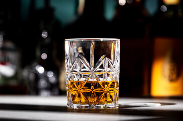 Scotch whiskey glass on dark green background with strong alcoholic drinks set. Spirits, liqueurs, distillates etc. in glasses and bottles.