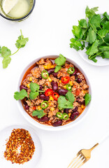 Spicy beef chili con carne with red beans, sweet corn, fresh cilantro, jalapeno pepper and tomato, served on white table, top view