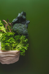 Fresh vegetables like broccoli, lettuce, and asparagus are displayed on a dark green background, highlighting healthy choices.