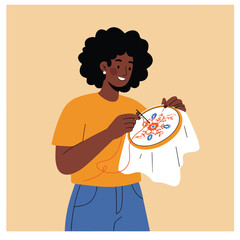 Woman smiles while embroidering floral design on a round frame
