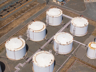 Seven white storage tanks at industrial site during daytime