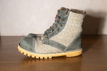 Side view of repaired rustic boots made from recycled nubuck leather and burlap fabric. Sustainable fashion and zero waste lifestyle concept.