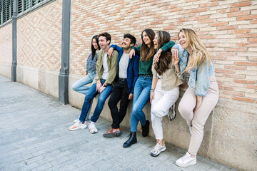 Obraz premium Young group of student people leaning against a brick wall. Youth community and friendship concept