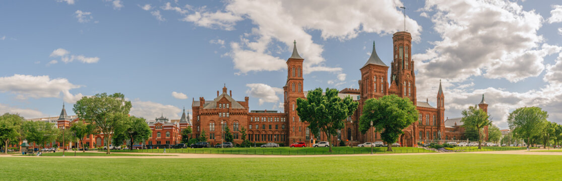 Visitors walk along the grassy National Mall near the red sandstone Smithsonian Institution Building, pano