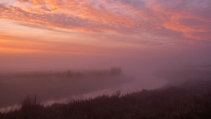 sunrise on the grassland and river with mist 