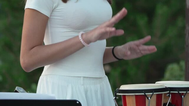 Drum music percussion, young girl playing bongos outdoors at a concert