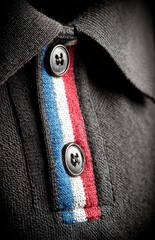 Close-up of a dark gray polo shirt with a red, white, and blue stripe detail on the collar