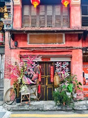 Colorful Red Chinese Shopfront With Lanterns, Floral Decor, And Vintage Wooden Doors in George Town, Penang