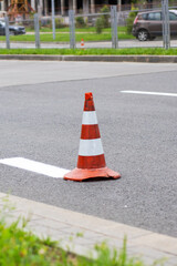 A red and white traffic cone can be seen placed on the side of the road