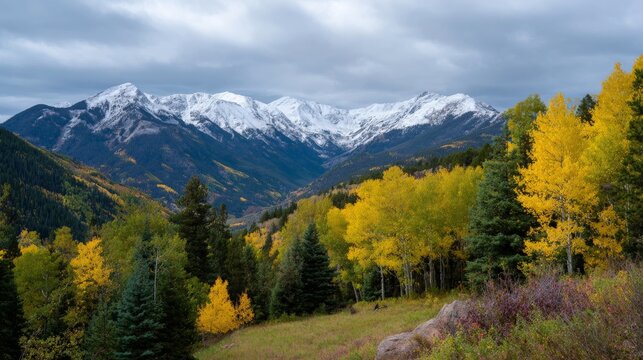 Majestic snow-capped mountains with vibrant autumn foliage and pine trees under cloudy sky - Powered by Adobe