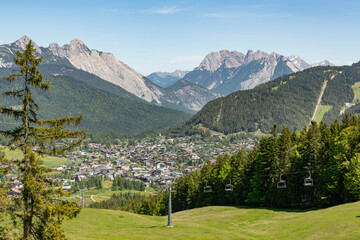 31 may 2025, Seefeld, Austria. View on Seefeld in Tirol village, in the valley between impressive alpine mountains. View from grassy hill on the town, pine tree at the side. Beautiful tourist must-see