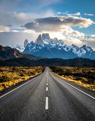 Fototapeta premium Empty road leading to snowy peaks