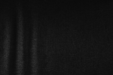 Dark black fabric texture background with soft folds and shadows, minimalist backdrop for design, presentation, advertising, and modern graphic projects.